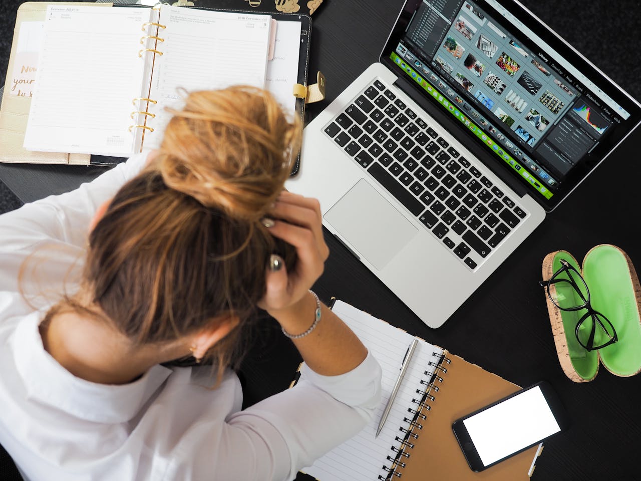 woman sitting in front of a macbook stressing out about work flow and productivity.